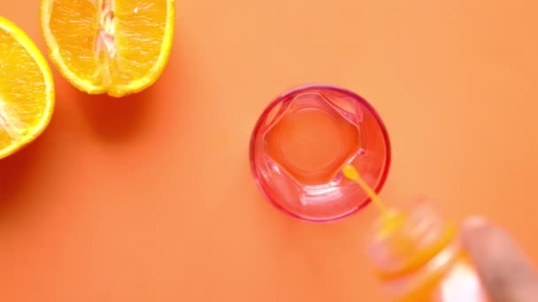 다양 한 색깔의 배경 위에 오렌지 주스를 붓는 모습 — 비디오