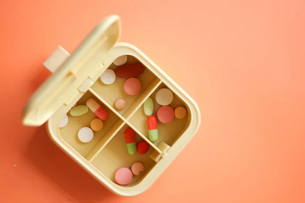 Primer plano de las píldoras médicas en una caja de pastillas sobre fondo naranja —  Fotos de Stock