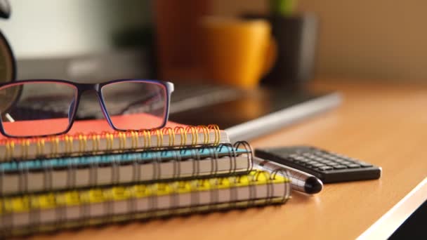 Bloc de notas, anteojos y un lápiz sobre una mesa de madera — Vídeo de stock