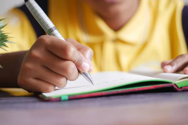 Kind hand schrijven op notitieblok shile zittend — Stockfoto