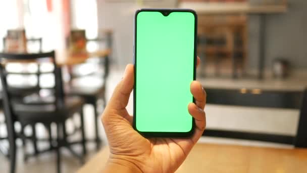 Mladý muž ruka pomocí chytrý telefon se zelenou obrazovkou v kavárně — Stock video