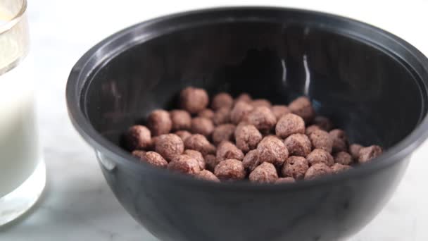 Turnarea laptelui în cereale dulci de ciocolată într-un castron pe masă — Videoclip de stoc
