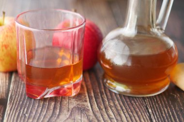 Cam şişede elma sirkesi ve masada taze yeşil elma. 