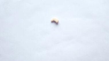 Beyaz arkaplana düşen kaju fıstıklarının yavaş çekimleri 