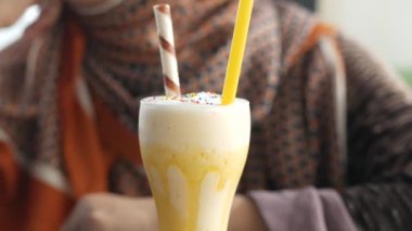 Masada muzlu mango milkshake ve arka planda genç kadınlar. 