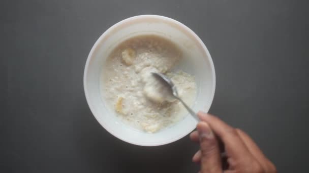 Hafer, Banane und Milch in einer Schüssel auf schwarzem Hintergrund — Stockvideo