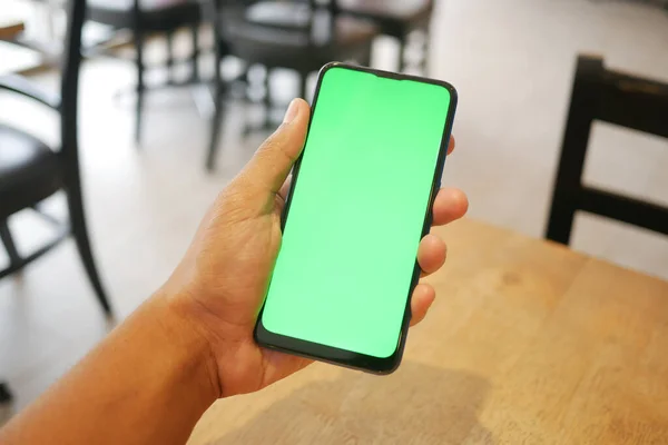Junger Mann bedient Smartphone mit grünem Bildschirm im Café — Stockfoto