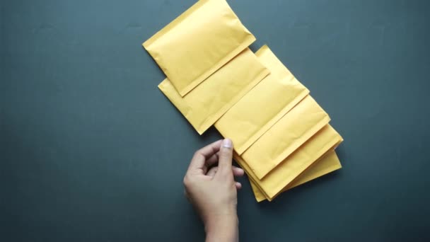 Masadaki sarı kağıt baloncuk zarfını elle seç — Stok video