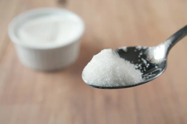 Белый сахар на ложке печени — стоковое фото