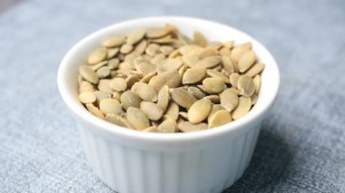  Siyah arka planda küçük bir kasede kabak tohumları 