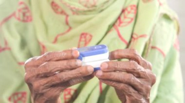 Yaşlı genç kadınların ellerinde nabız oksimetresi var..