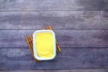 Ahşap masa manzaralı bir kapta taze tereyağı. .