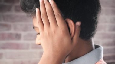 teenage boy having ear pain touching his painful ear 