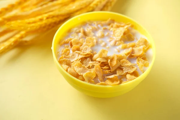 corn flakes and milk in a yellow color bowl ,