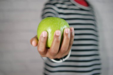 Siyah arka planda yeşil elmayı tutan ,