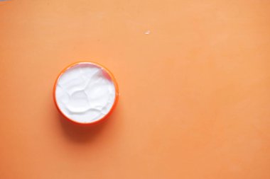 Turuncu bir kaptaki güzellik kremini kapat. ,