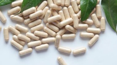 Bitkisel ilaç kapsülünün beyaza düşüşünün üst görüntüsü ,