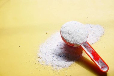 Mavi arka planda plastik kaşıkla yıkama tozu ,