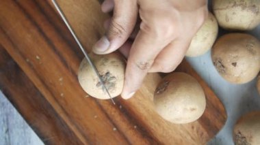 Sapodilla meyvesi masanın üzerinde doğranır. ,