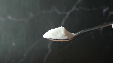 Yavaş çekimde beyaz şeker kaşıktan dökülüyor. .
