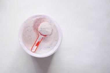 Siyah arka planda plastik kaşıkla yıkama tozu.