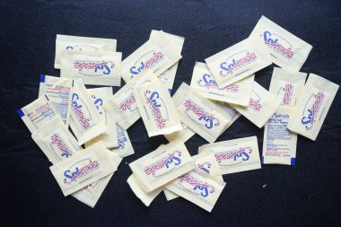 Siyah arka planda bir kaşık beyaz tatlandırıcı 