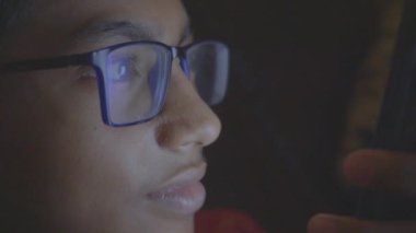  Genç çocuk geceleri akıllı telefon kullanarak kanepede oturuyor. .