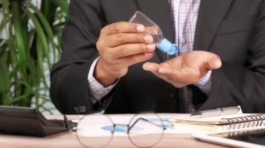 İş adamı ofis masasında dezenfektan jeli kullanıyor..