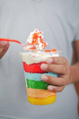 young men eating rainbow color cake .