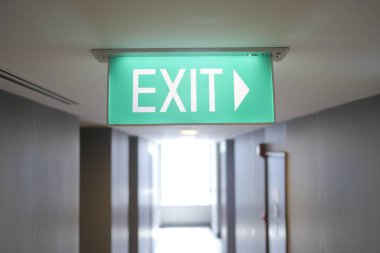 Fire exit sign in the middle of the the corridor in building,