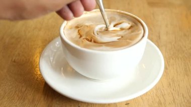 İnsan, kaşıkla kahve karıştırır.