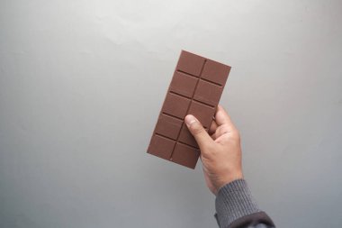 Gri arka planda siyah çikolatayı altın rengine boyayan erkeklerin üst görüntüsü ,