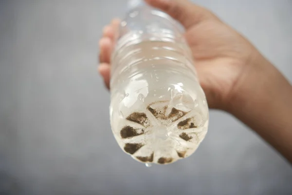 Sosteniendo Sucia Botella Agua Sobre Fondo Negro — Foto de Stock