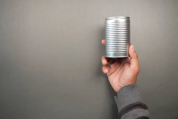 man holding a canned food on black background .