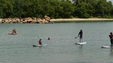 Gün batımında sörf yapan bir grup insan 