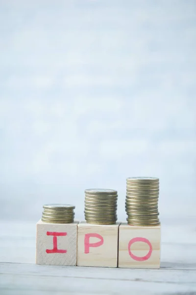 IPO text ,Initial Public Offering on wooden block with stack of coins.