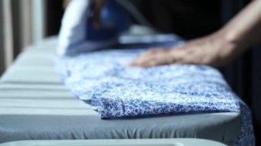  women hands ironing clothes with iron on ironing board.