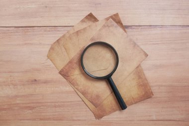  empty old paper and magnifying glass on table..