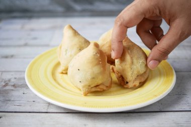 hand pick a indian food singara on plate .