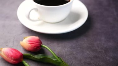 Siyah arka planda pembe lale ve kahve fincanı ,