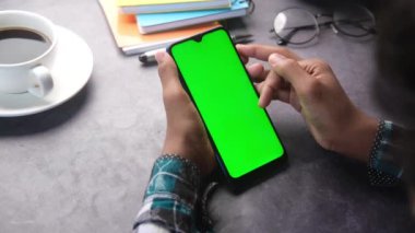 Ofis masasında akıllı telefon kullanan bir adamın üst görüntüsü..