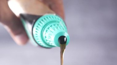  close up of maple syrup pouring from a container .