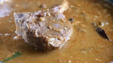 cooking traditional Indian curry lamb masala in a cooking pan ,