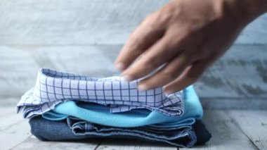 men hand putting shirts on table .