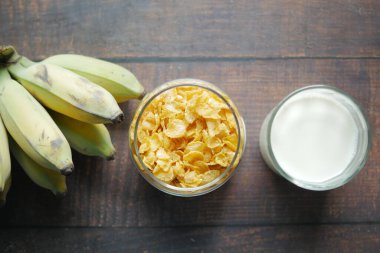  Top view of corn flakes , banana and milk on table ,