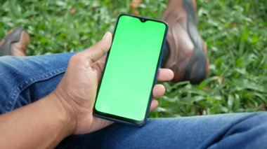 Açık havada akıllı telefon kullanan genç bir adamın dikiz görüntüsü .