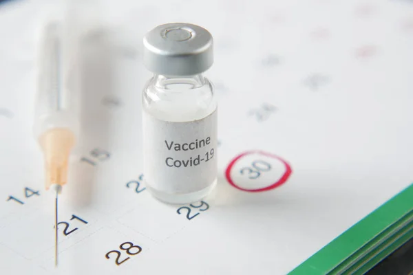 Close up of coronavirus vaccine and syringe on black background.