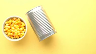 Sweet corns in a bowl and tin container on yellow background ,