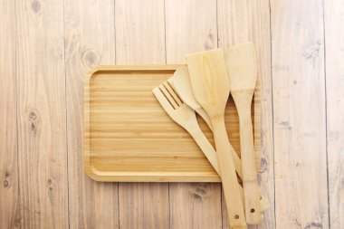  wooden cutlery fork and spoon on a chopping board on table ,