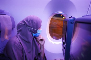 women with a face mask sitting on airplane seats in the cabin,